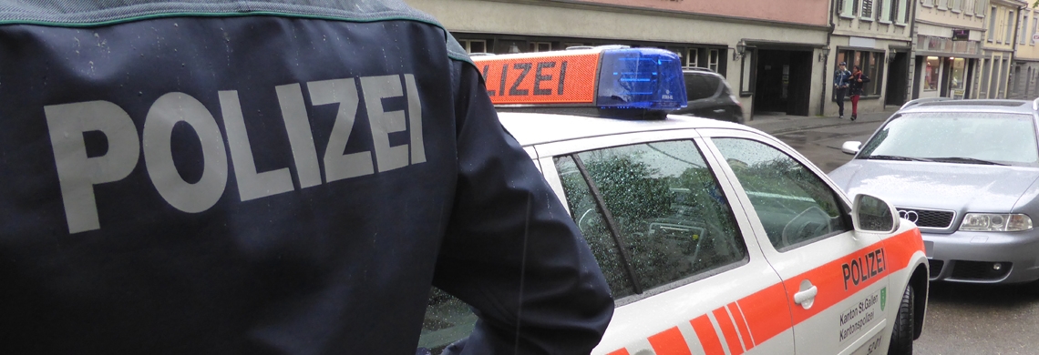 Symbolbild: Polizist steht vor Polizeiauto